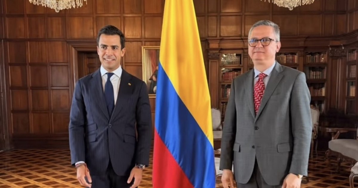 Juan Gonzalo Ospina en la ceremonia oficial con la bandera de Colombia y un representante de la Cancillería