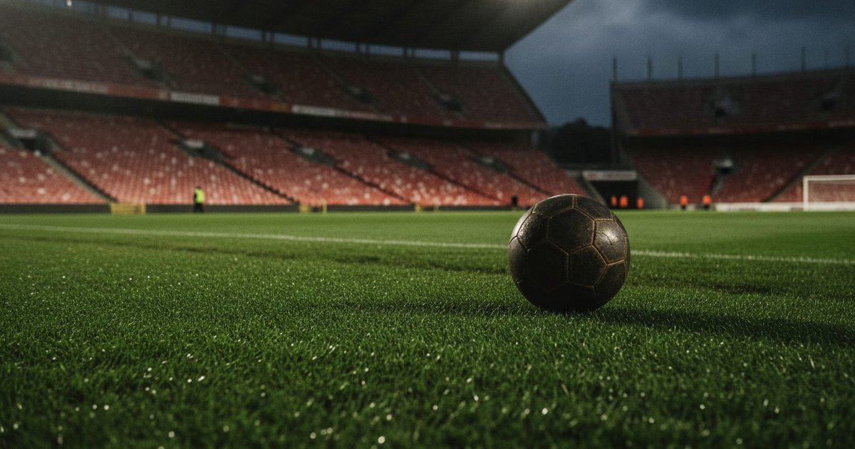 Balón de fútbol en un campo de césped en un estadio, con las luces de los focos creando un ambiente de partido nocturno.